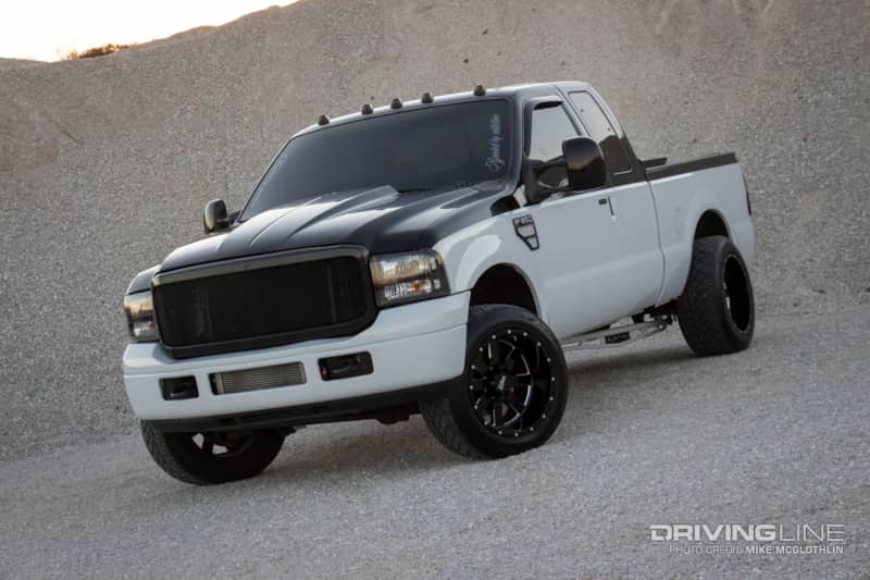 Black and white 2006 Ford F-350 with large wheels and tires