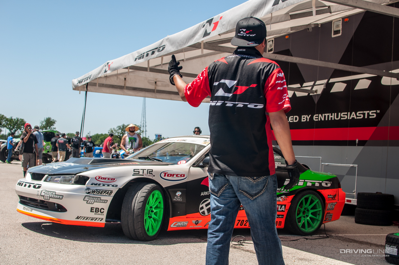 Man standing in front of a drift race car and a Nitto booth
