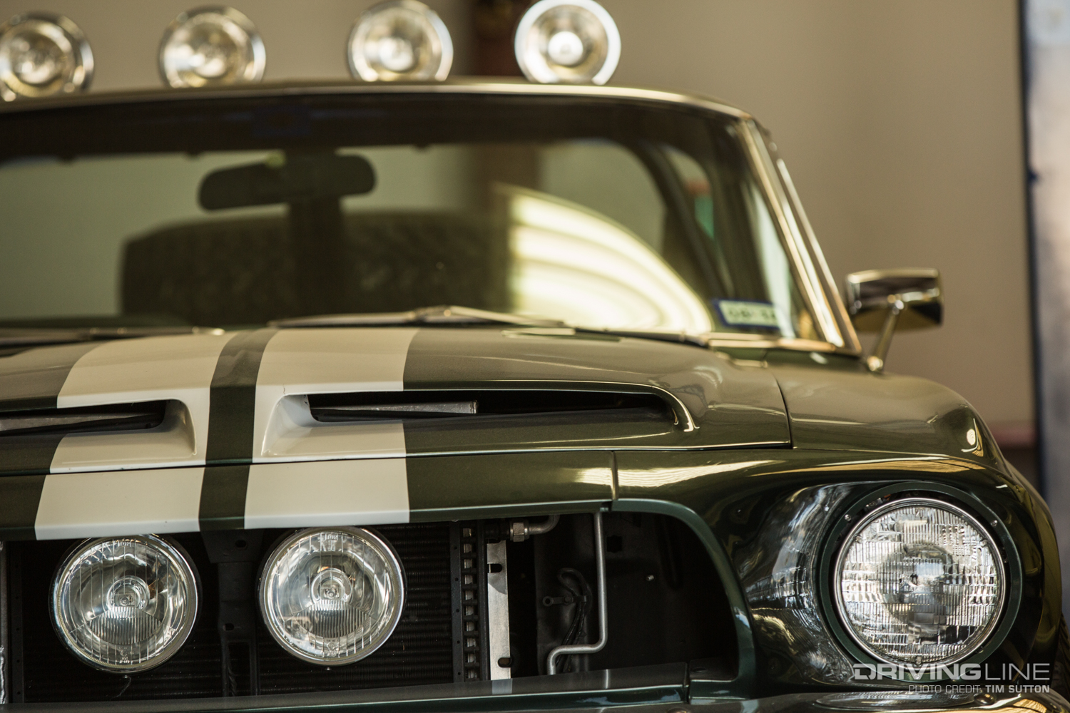 Front of a black Ford Mustang with white racing stripes