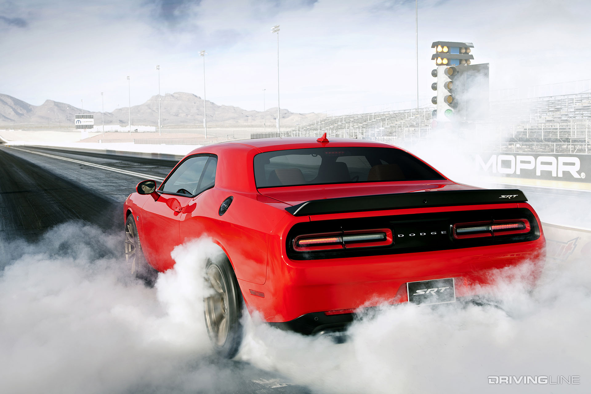 Red Challenger doing a burnout on a dragstrip