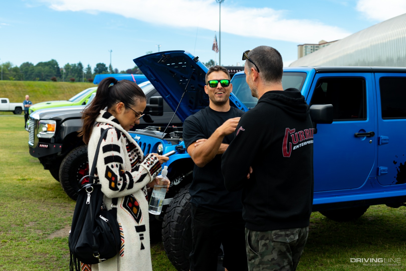 Three people talking in front of a Jeep Wrangler at Rigstock