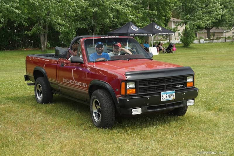 Red Dodge Dakota Sport Convertible driving on grass.