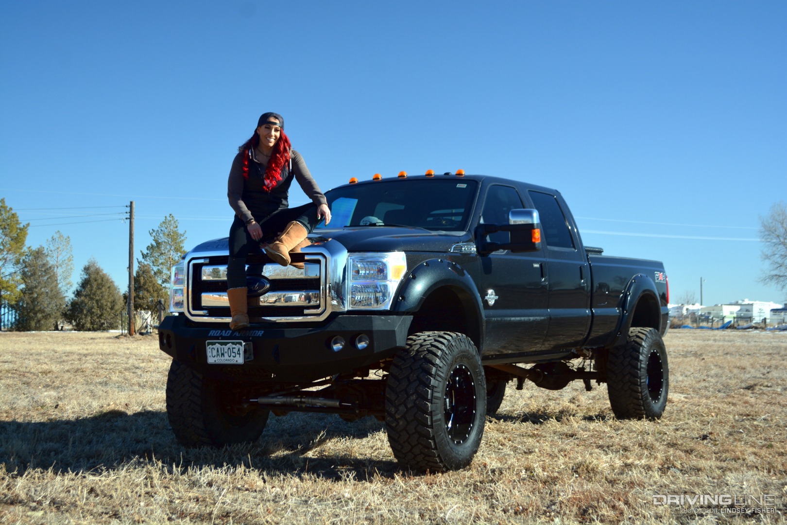 Lifted 2011 Ford F350 in field with Monica Coakley (owner) sitting on the hood