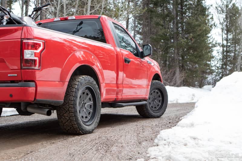 Nitto Recon Grappler A/T Tires on a Ford F150 with a motorcycle in the bed on snow muddy road