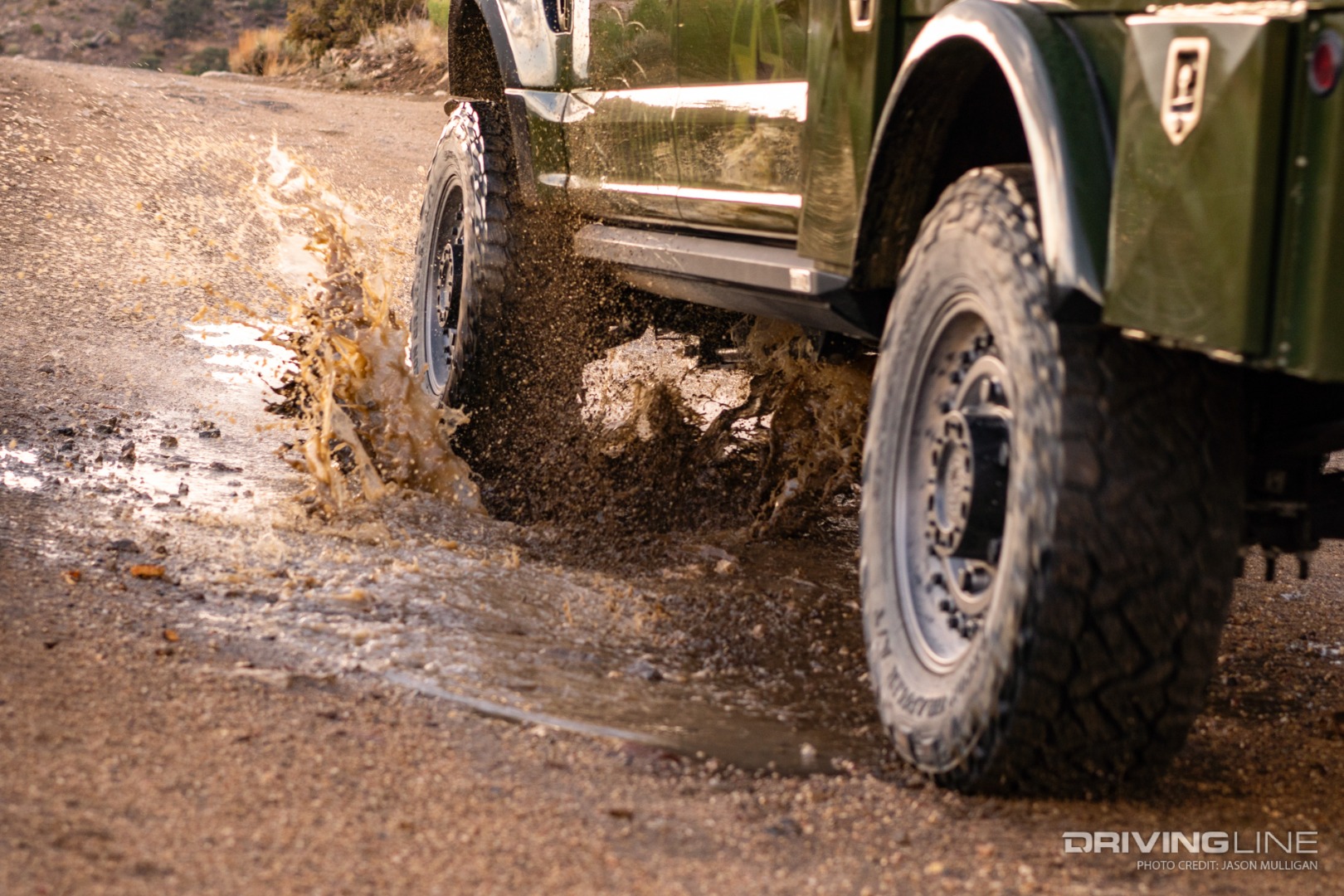 Nitto Recon Grappler A/T tires driving through a puddle on a dirt road