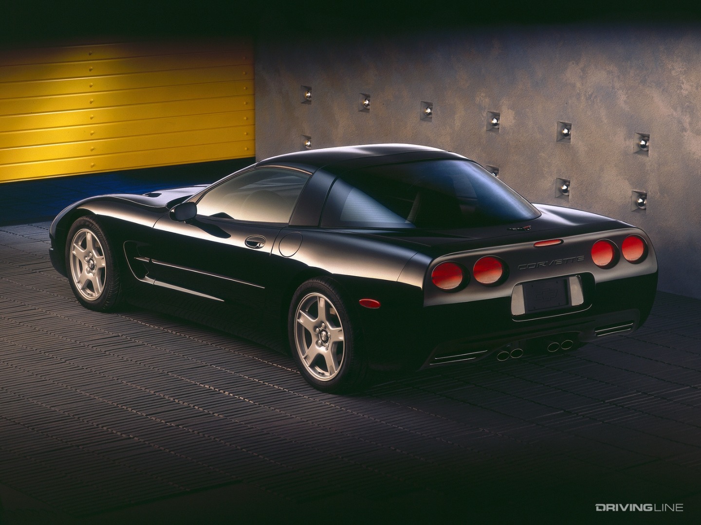 Chevrolet Corvette C5 black in front of steel wall