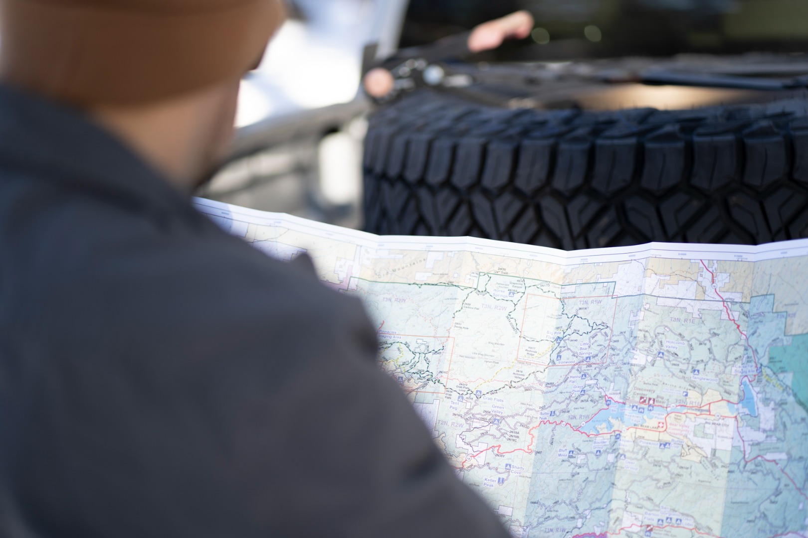 A man reading a paper map in front of a pickup bed