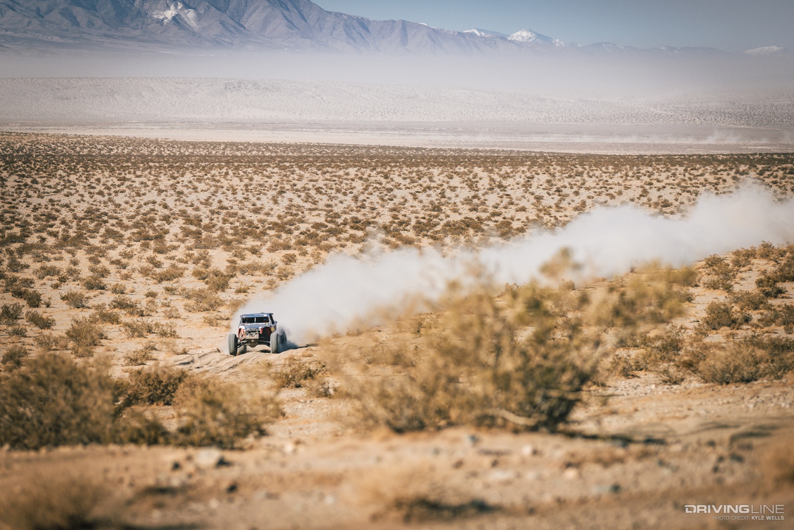 Jason Scherer driving across the desert with a dust trail behind him