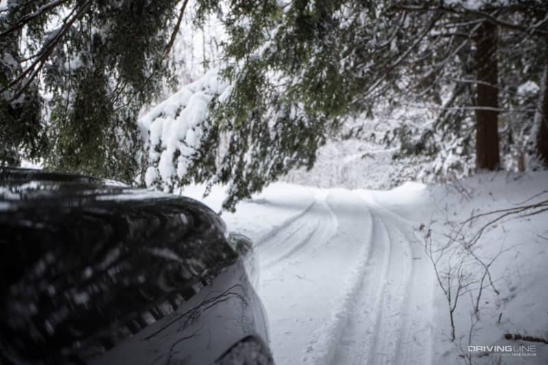The front of a car looking out over a snowy trail