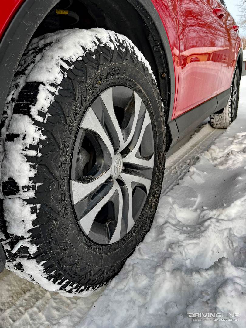 Nitto Nomad Grappler tire covered in snow on a red Toyota Rav4