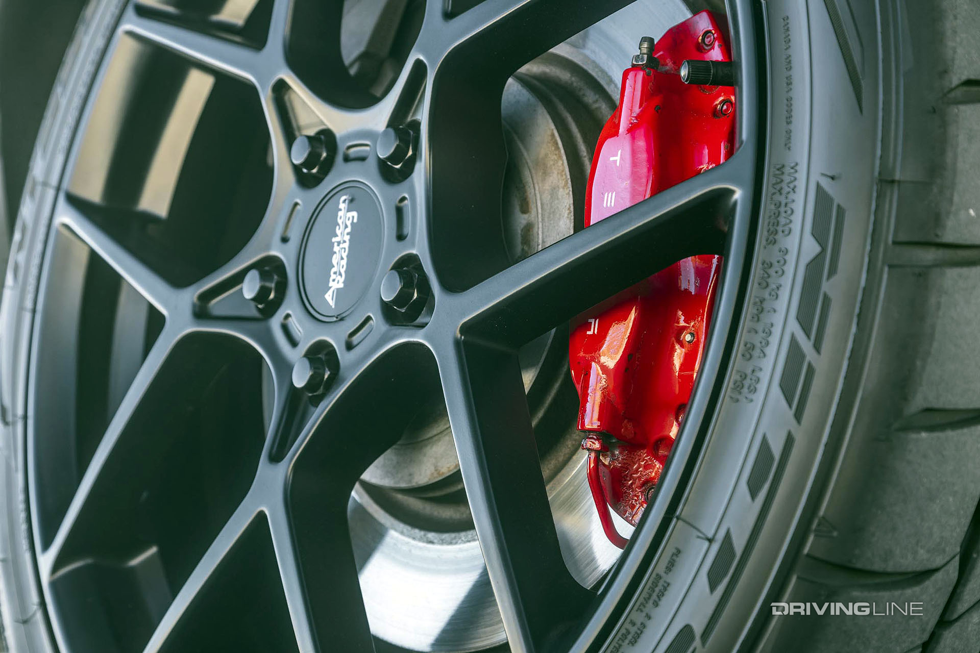 close up on american racing wheel hub nitto tire tesla caliper