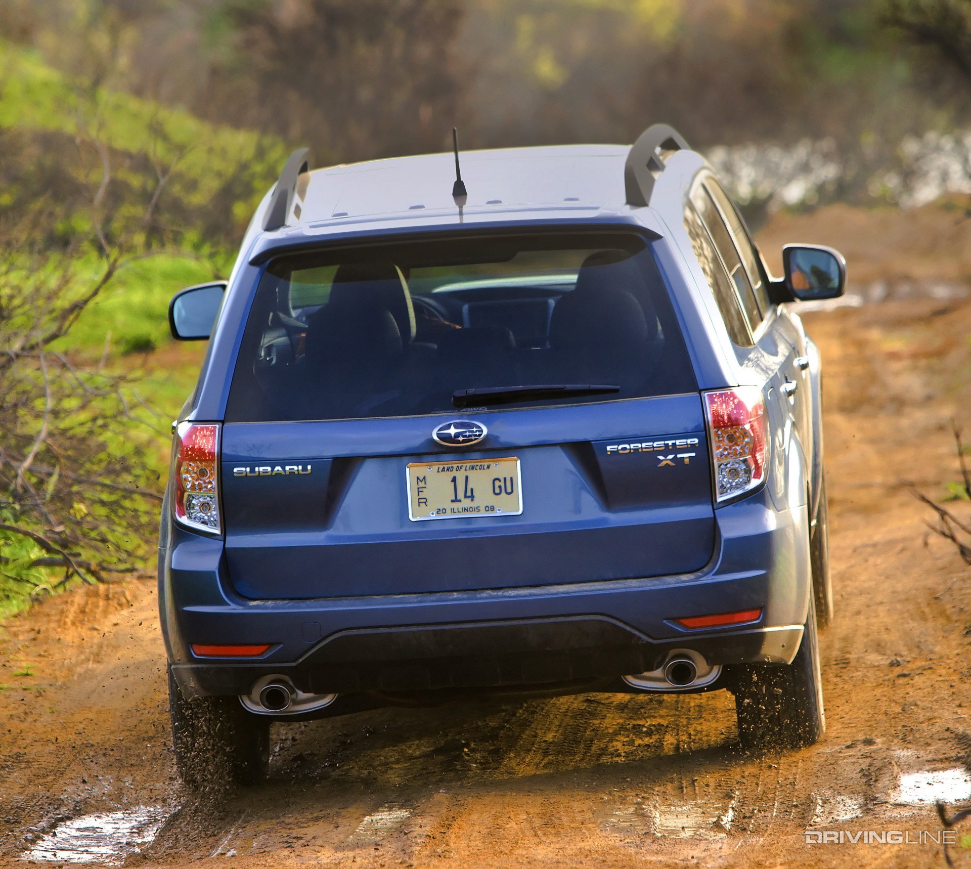 Subaru Forester climbing muddy road from behind