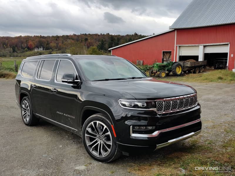 2023 Jeep Grand Wagoneer L parked on a farm with tractor in the background