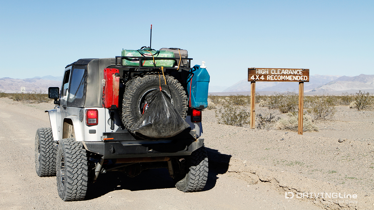 "High Clearance 4x4 Recommended" sign and Jeep Wrangler on Harry Wade Exit Route in Death Valley National Park