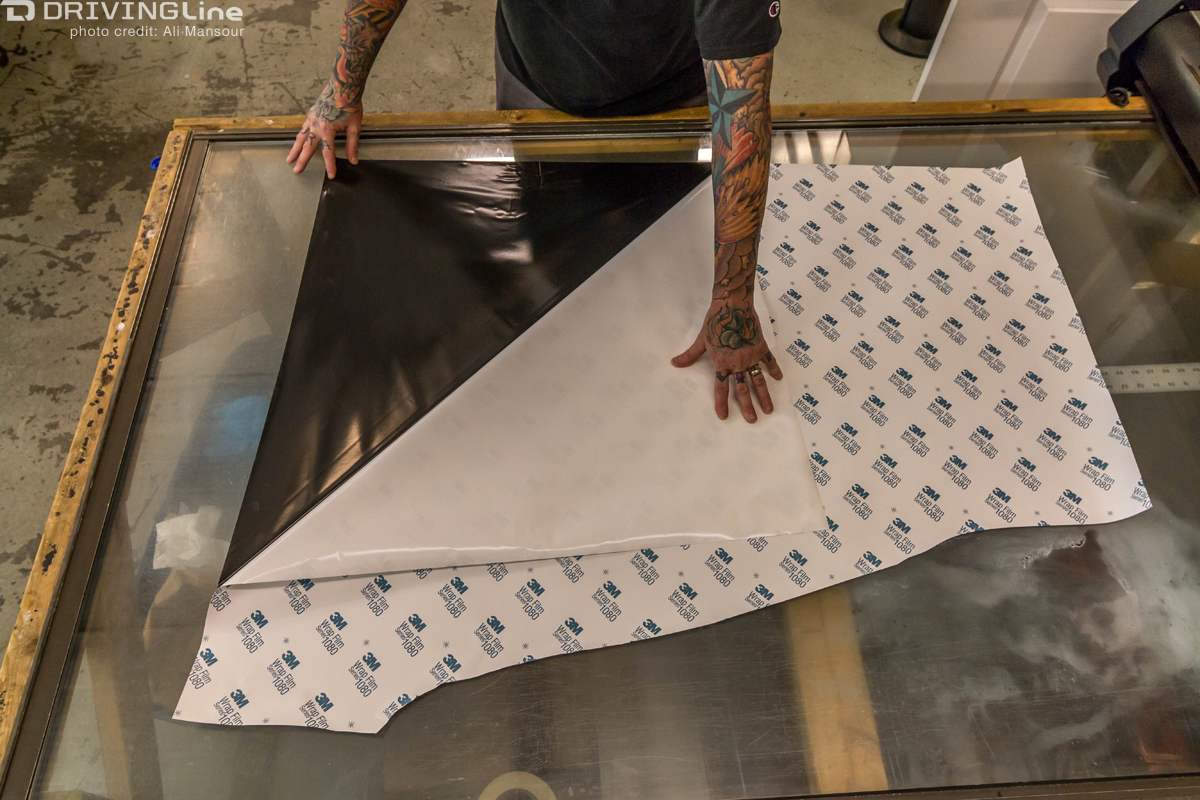 Man pealing back backing on the 3M 1080 Satin Black vehicle wrap