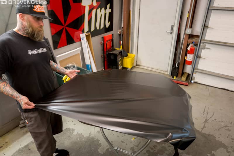 Man streching the 3M 1080 Satin Black vehicle wrap over the Jeep Wrangler JK door
