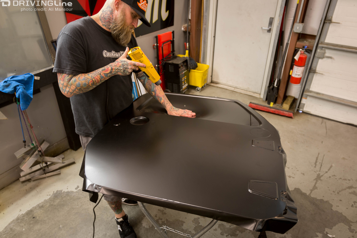 Man using a heat gun to install the 3M 1080 Satin Black vehicle wrap on a Jeep Wrangler JK door
