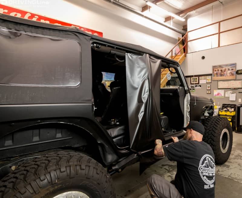 Man instnalling a 3M 1080 Satin Black vehicle wrap on the exterior of a Jeep Wrangler JK