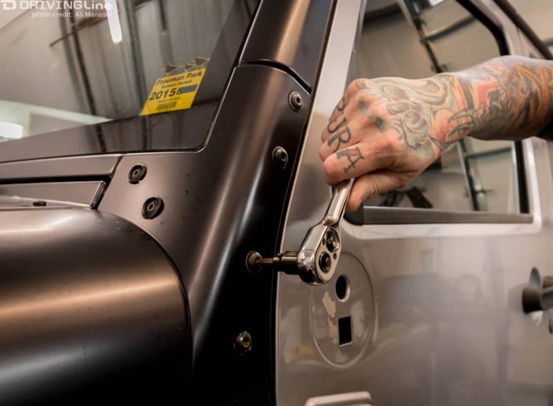 Hand using a torque wrench on a bolt on the exterior of a Jeep Wrangler JK