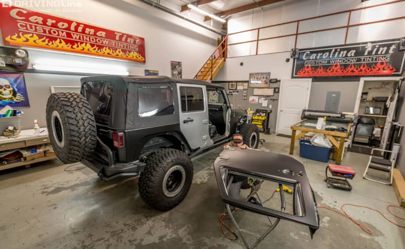 Jeep Wrangler in a shop with its door off and 3M 1080 Satin Black vehicle wrap on it