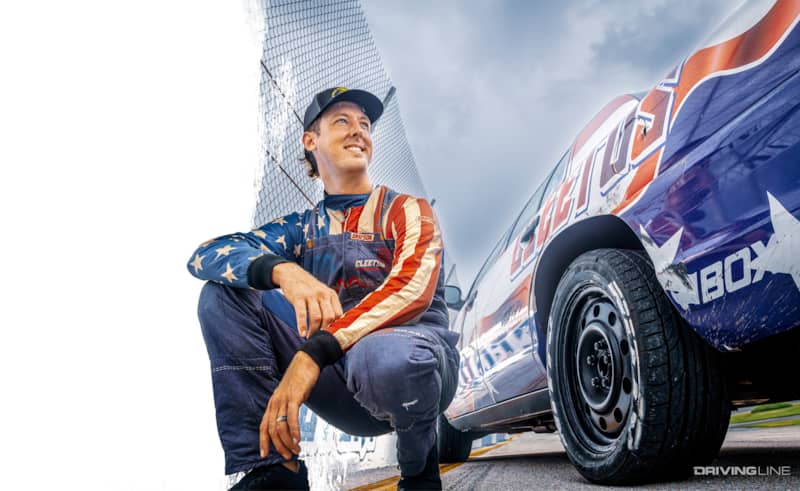 CLeetus McFarland crouching down next to a Nitto Tire mounted on his Ford Crown Victoria