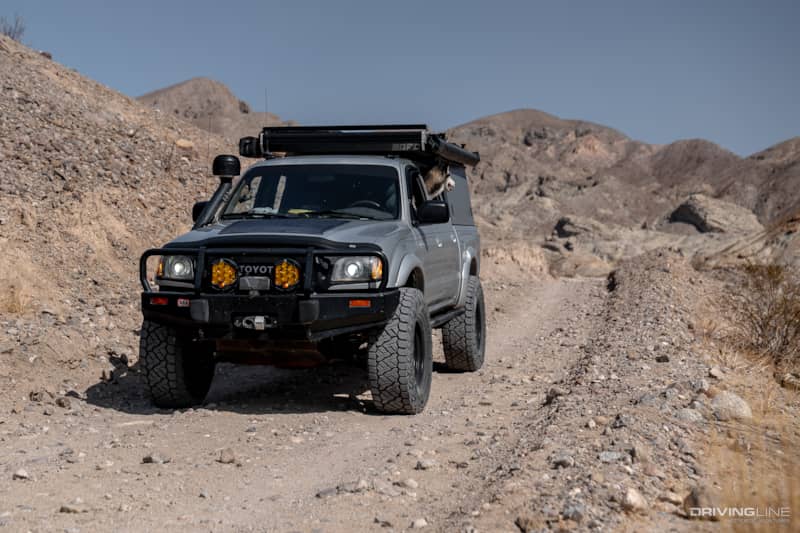 Silver Toyota Tacoma with dog on dirt and rock trail
