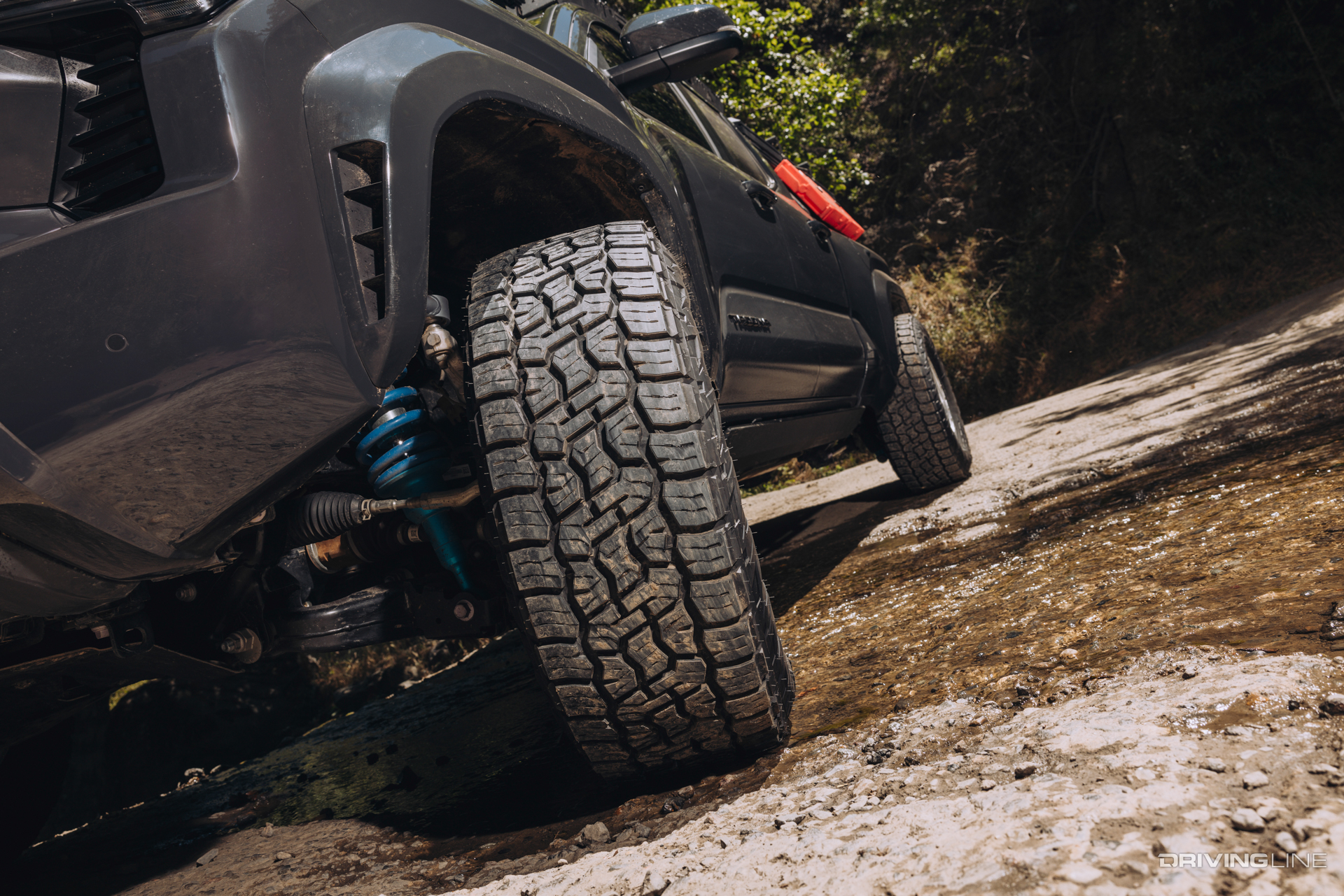Tread detail of Nitto Terra Grappler G3 tire on a Toyota Tacoma driving through a stream