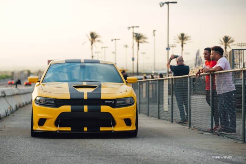 Dodge Charger in yellow facing camera head-on with crowd to the right