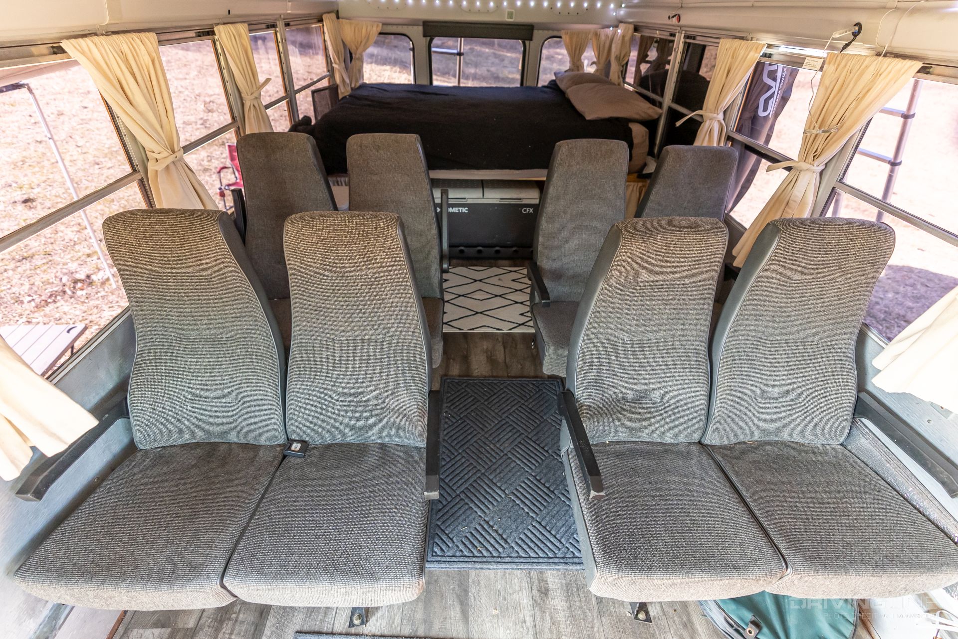 Converted school bus interior layout with queen bed and coach house seats